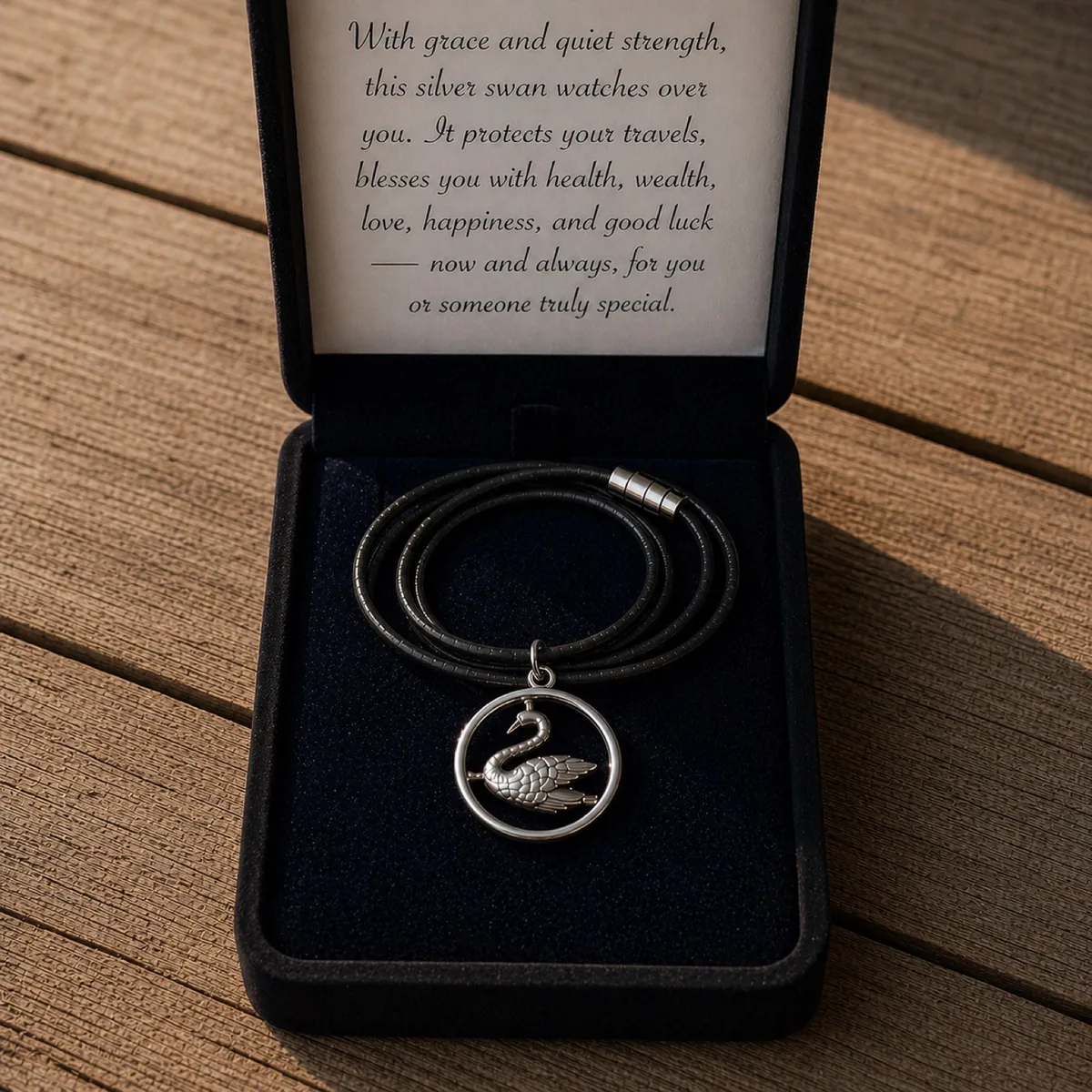 The Swan in the Circle pendant resting in its presentation box beside the certificate card