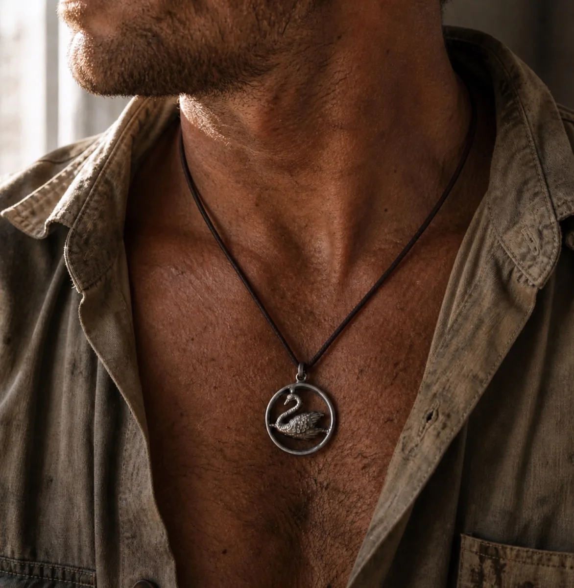 The Swan in the Circle silver pendant worn on a leather cord against an open collar